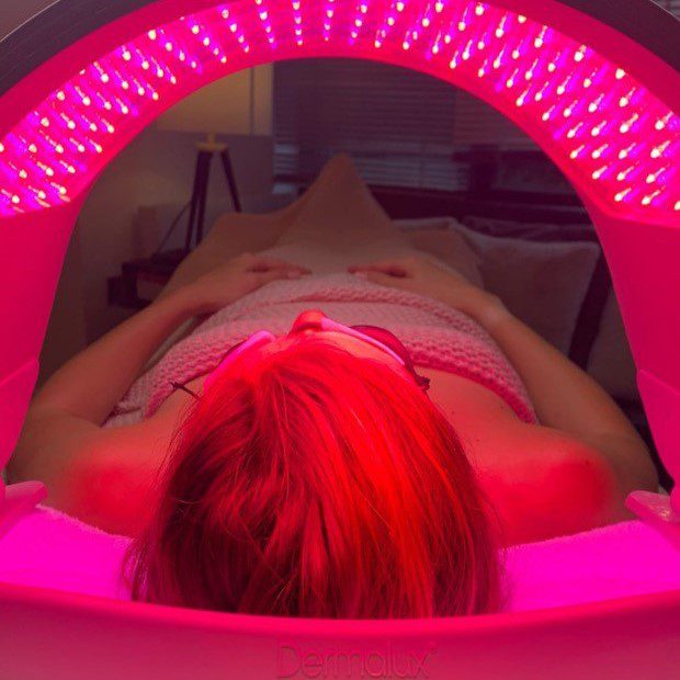 Woman lying under the Dermalux LED Phototherapy Flex device.